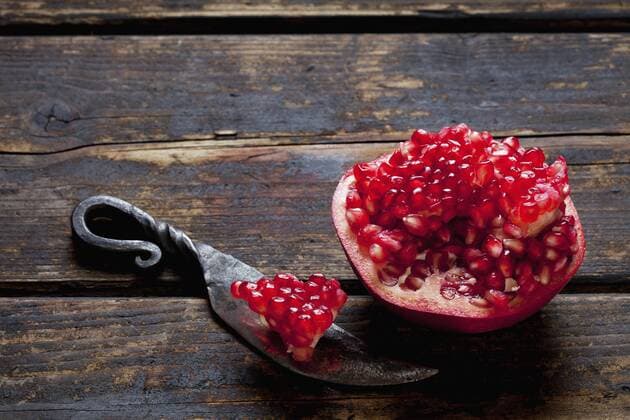 Sliced pomegranate and a knife on dark wood  CSF026676