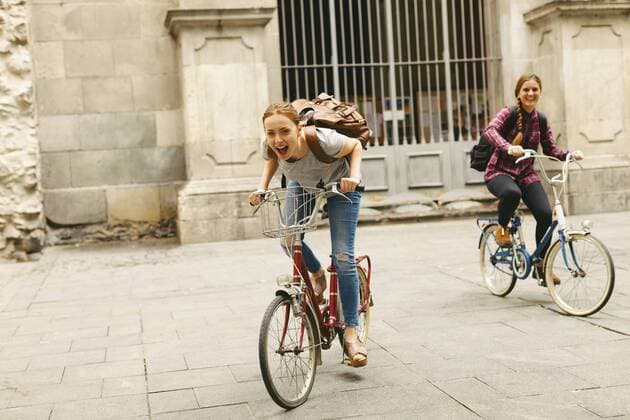Spain, Barcelona, two happy young women riding bicycle in the city  EBSF000970