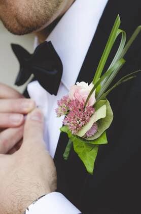 Groom with buttonhole flowers buttoning his shirt  GEMF000458