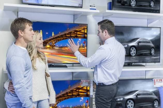 Model Released: Beratung im Elektronikfachgeschäft Shop assistant showing flatscreen TVs to young couple model released Symbolfoto property released  ZEF007472