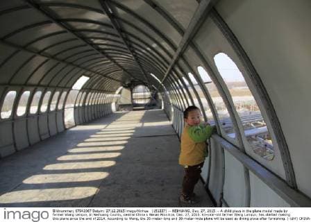 (151227) -- NEIHUANG, Dec. 27, 2015 -- A child plays in the plane model made by farmer Wang Lanqun, in Neihuang County, central China s Henan Province, Dec. 27, 2015. 61-year-old farmer Wang Lanqun, has started making this plane since the end of 2014. According to Wang, the 35-meter-long and 38-meter-wide plane will be used as dining place after furnishing. ) (dhf) CHINA-HENAN-FARMER-PLANE MODEL (CN) LiuxXiaokun 