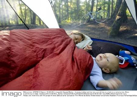 A young mother and her one year old boy in a tent on a camping trip. Mom is still trying to sleep. Rosebery Provincial Park, British Columbia  acp79394 StevexOgle