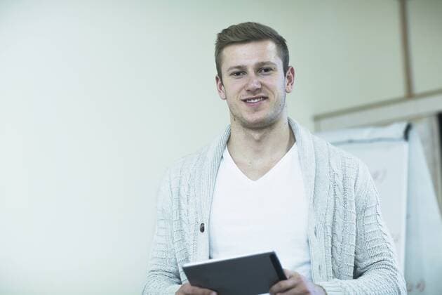 Young male teacher working on a digital tablet in classroom, Freiburg Im Breisgau, Baden-Württemberg, Germany mit_2024_00069