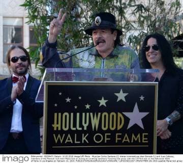 Musician Carlos Santana (C) makes comments as Alex Gonzale (L) and Juan Calleros, members of the Mexican rock band Mana look on during an unveiling ceremony honoring the group with the 2,573rd star on the Hollywood Walk of Fame in Los Angeles on February 10, 2016.  LAP2016021007 JIMxRUYMEN