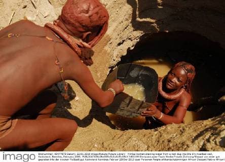 Himba women drawing water from a well dug into the dry riverbed well, Kaokoland, Namibia, February 2005.  1451194 EnriquexLopez-Tapia