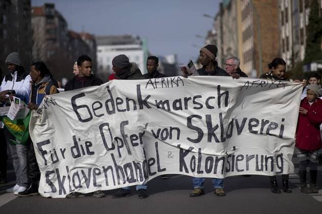 Gedenkmarsch Kolonialgeschichte DEU, Deutschland, Germany, Berlin, 27.02.2016 Demonstranten mit Transparent beim 10. Gedenkmarsch zur Erinnerung an die afrikanischen Opfer von Versklavung, Kolonialismus und rassistischer Gewalt vom Komitee fuer ein afrikanisches Denkmal in Berlin und afrikanischer Vereine in Berlin. Dieser Gedenkmarsch wurde ins Leben gerufen, um der Forderung nach Anerkennung der Verbrechen gegen Schwarze Menschen und Menschen afrikanischer Herkunft Nachdruck zu verleihen. Anlass ist die Berliner Afrika-Konferenz von 1884 - 1885, auf der Afrika vor 130 Jahren unter den europaeischen Kolonialmaechten aufgeteilt wurde. Mehr als 30 Millionen Afrikanerinnen und Afrikaner wurden Opfer von Versklavung und kolonialen Verbrechen gegen die Menschlichkeit. Die von Deutschland an den Herero und Nama begangenen Voelkermorde in Namibia und die Kriegsverbrechen in Tansania im Maji- M
