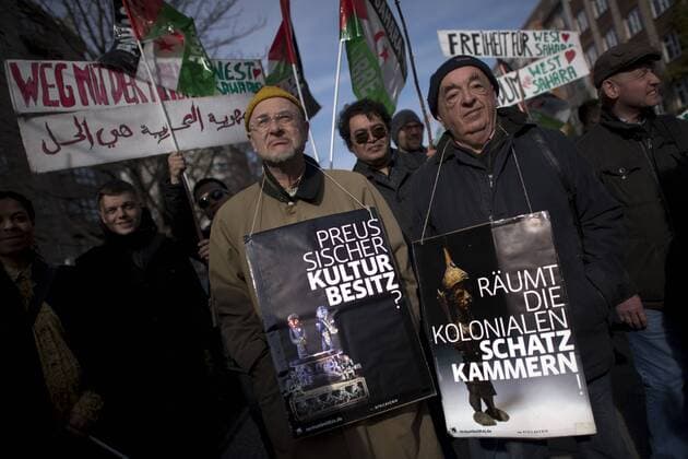 Gedenkmarsch Kolonialgeschichte DEU, Deutschland, Germany, Berlin, 27.02.2016 Demonstrant mit Plakat Preussischer Kulturbesitz und raeumt die kolonialen Schatzkamamern gegen die Kolobialgeschichte und die Aneigung afrikanischer Kulturgueter durch deutsche Museen und dem Humboldt Forum beim 10. Gedenkmarsch zur Erinnerung an die afrikanischen Opfer von Versklavung, Kolonialismus und rassistischer Gewalt vom Komitee fuer ein afrikanisches Denkmal in Berlin und afrikanischer Vereine in Berlin. Dieser Gedenkmarsch wurde ins Leben gerufen, um der Forderung nach Anerkennung der Verbrechen gegen Schwarze Menschen und Menschen afrikanischer Herkunft Nachdruck zu verleihen. Anlass ist die Berliner Afrika-Konferenz von 1884 - 1885, auf der Afrika vor 130 Jahren unter den europaeischen Kolonialmaechten aufgeteilt wurde. Mehr als 30 Millionen Afrikanerinnen und Afrikaner wurden Opfer von Versklavung