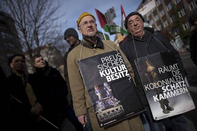 Gedenkmarsch Kolonialgeschichte DEU, Deutschland, Germany, Berlin, 27.02.2016 Demonstrant mit Plakat Preussischer Kulturbesitz und raeumt die kolonialen Schatzkamamern gegen die Kolobialgeschichte und die Aneigung afrikanischer Kulturgueter durch deutsche Museen und dem Humboldt Forum beim 10. Gedenkmarsch zur Erinnerung an die afrikanischen Opfer von Versklavung, Kolonialismus und rassistischer Gewalt vom Komitee fuer ein afrikanisches Denkmal in Berlin und afrikanischer Vereine in Berlin. Dieser Gedenkmarsch wurde ins Leben gerufen, um der Forderung nach Anerkennung der Verbrechen gegen Schwarze Menschen und Menschen afrikanischer Herkunft Nachdruck zu verleihen. Anlass ist die Berliner Afrika-Konferenz von 1884 - 1885, auf der Afrika vor 130 Jahren unter den europaeischen Kolonialmaechten aufgeteilt wurde. Mehr als 30 Millionen Afrikanerinnen und Afrikaner wurden Opfer von Versklavung