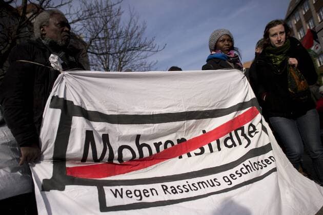 Gedenkmarsch Kolonialgeschichte DEU, Deutschland, Germany, Berlin, 27.02.2016 Demonstranten mitTransparent Mohrenstrasse wegen Rassismus geschlossen fuer die Umbennenung von Strassennamen beim 10. Gedenkmarsch zur Erinnerung an die afrikanischen Opfer von Versklavung, Kolonialismus und rassistischer Gewalt vom Komitee fuer ein afrikanisches Denkmal in Berlin und afrikanischer Vereine in Berlin. Dieser Gedenkmarsch wurde ins Leben gerufen, um der Forderung nach Anerkennung der Verbrechen gegen Schwarze Menschen und Menschen afrikanischer Herkunft Nachdruck zu verleihen. Anlass ist die Berliner Afrika-Konferenz von 1884 - 1885, auf der Afrika vor 130 Jahren unter den europaeischen Kolonialmaechten aufgeteilt wurde. Mehr als 30 Millionen Afrikanerinnen und Afrikaner wurden Opfer von Versklavung und kolonialen Verbrechen gegen die Menschlichkeit. Die von Deutschland an den Herero und Nama be