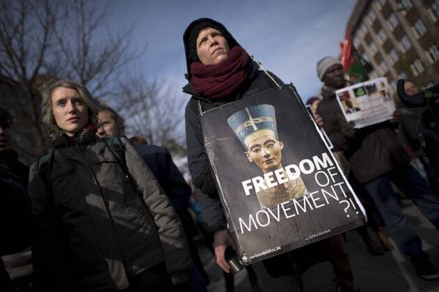 Gedenkmarsch Kolonialgeschichte DEU, Deutschland, Germany, Berlin, 27.02.2016 Demonstrant mit Plakat Freedom of Movement und Foto der Nofretete gegen die Kolobialgeschichte und die Aneigung afrikanischer Kulturgueter durch deutsche Museen und dem Humboldt Forum beim 10. Gedenkmarsch zur Erinnerung an die afrikanischen Opfer von Versklavung, Kolonialismus und rassistischer Gewalt vom Komitee fuer ein afrikanisches Denkmal in Berlin und afrikanischer Vereine in Berlin. Dieser Gedenkmarsch wurde ins Leben gerufen, um der Forderung nach Anerkennung der Verbrechen gegen Schwarze Menschen und Menschen afrikanischer Herkunft Nachdruck zu verleihen. Anlass ist die Berliner Afrika-Konferenz von 1884 - 1885, auf der Afrika vor 130 Jahren unter den europaeischen Kolonialmaechten aufgeteilt wurde. Mehr als 30 Millionen Afrikanerinnen und Afrikaner wurden Opfer von Versklavung und kolonialen Verbrech