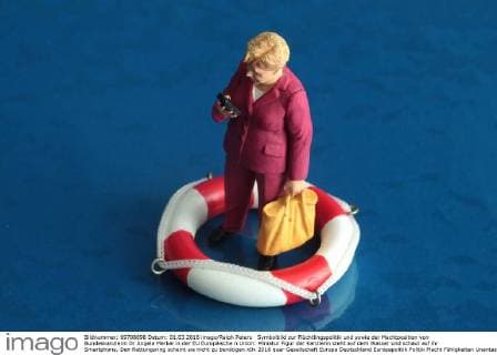 Symbolbild zur Flüchtlingspolitik und sowie der Machtposition von Bundeskanzlerin Dr Angela Merkel in der EU Europäische n Union: Miniatur Figur der Kanzlerin steht auf dem Wasser und schaut auf ihr Smartphone. Den Rettungsring scheint sie nicht zu benötigen
