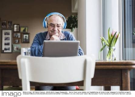 Senior man using laptop and headphones at home model released Symbolfoto property released  UUF006610