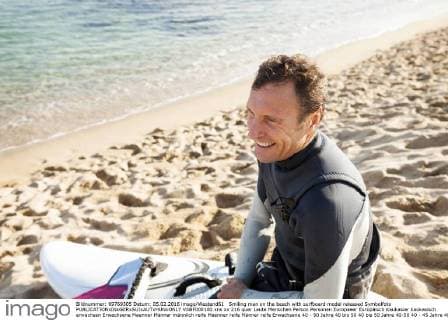 Smiling man on the beach with surfboard model released Symbolfoto  VABF000100