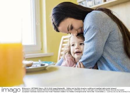 Mother and her little daughter cuddling at breakfast table model released Symbolfoto property released  HAPF000122