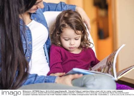 Portrait of little girl watching children s book with her mother model released Symbolfoto property released  HAPF000137
