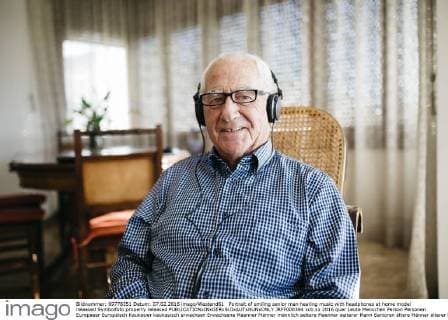 Portrait of smiling senior man hearing music with headphones at home model released Symbolfoto property released  JRFF000384