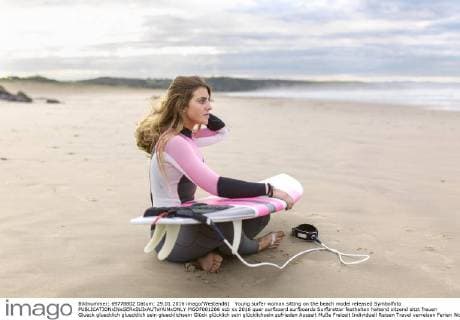 Young surfer woman sitting on the beach model released Symbolfoto  MGOF001286