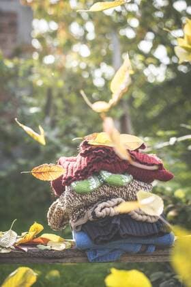 Stack of warm clothing and falling autumn leaves  DEGF000644