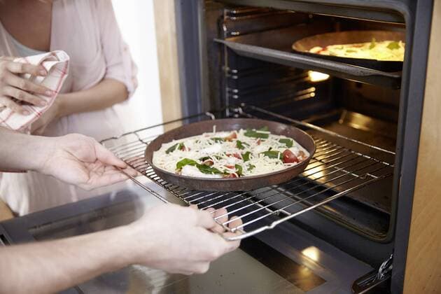 Couple putting pizza into oven model released Symbolfoto property released  FMKF002367