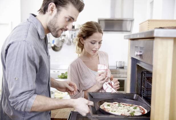 Couple putting pizza into oven model released Symbolfoto property released  FMKF002368
