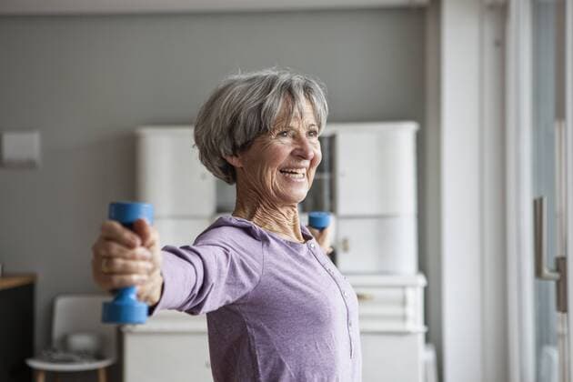 Portrait of happy senior woman doing fitness exercise with dumbbells at home model released Symbolfoto property released  RBF004152