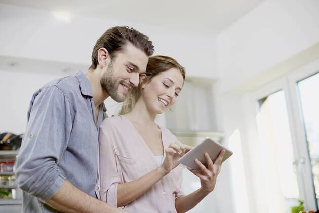 Smiling couple looking at digital tablet in kitchen model released Symbolfoto property released  FMKF002397