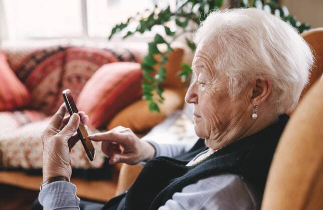 Senior woman sitting in the living room using smartphone model released Symbolfoto property released  GEMF000753