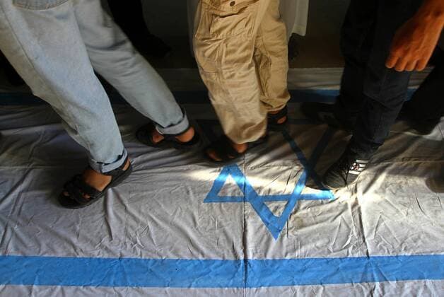 Sep. 29, 2011 - Gaza City, West Bank - Palestinian supporters of Popular Resistance Committees step on an Israeli flag during a rally to mark the 11th anniversary of Al-Aqsa Intifada (uprising) in Gaza city. Israel on Tuesday approved construction of 1,100 homes for Jews on the annexed land in the West Bank, a move that could complicate international efforts to renew peace talks and defuse a crisis over a Palestinian statehood bid at the United Nations. - ZUMAap3_