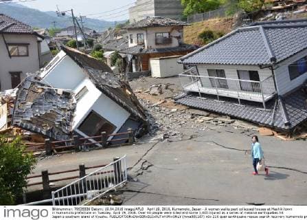 April 19, 2016, Kumamoto, Japan - A woman walks past collapsed houses at Mashiki town in Kumamoto prefecture on Tuesday, April 19, 2016. Over 40 people were killed and some 1,000 injured as a series of massive earthquakes hit Japan s southern island of Kyushu.  (lwxa001187)