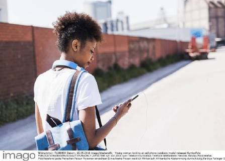 Young woman looking at cell phone outdoors model released Symbolfoto  UUF007306
