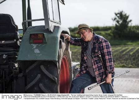 Farmer holding tool examining tractor tyre model released Symbolfoto  UUF007333