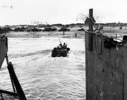A U.S. Army weapons carrier moves through the surf toward Utah Beach, after being launched from its landing craft on D-Day, June 6, 1944, during the Allied invasion of German-occupied France. Note .50 caliber machine gun on the vehicle, pointed skyward for anti-aircraft defense.  WAX2016060143 U.S.xArmyxSignalxCorps