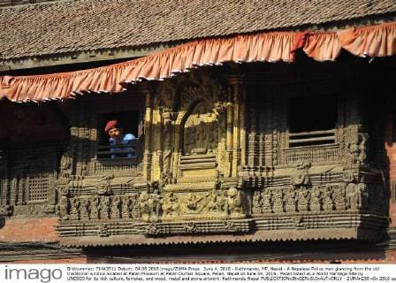 June 4, 2016 - Kathmandu, NP, Nepal - A Nepalese Police man glancing from the old traditional window located at Patan Museum at Patan Durbar Square, Patan, Nepal on June 04, 2016.. Patan listed as a World Heritage Site by UNESCO for its rich culture, temples, and wood, metal and stone artwork. Kathmandu Nepal  - ZUMAn230