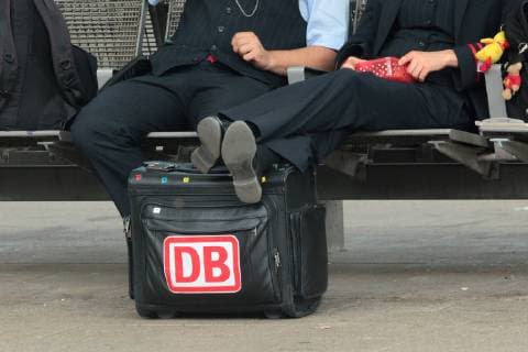 Zugbegleiter der DB Deutsche n Bahn AG machen eine Pause am Hauotbahnhof Frankfurt. Zugbegleiterin legt entspannt ihre Beine auf einem Koffer mi DB Logo, Hessen, Deutschland