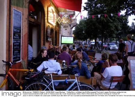 Fußballfans verfolgen das Eröffnungsspiel Frankreich gegen Rumänien anlässlich der Fußball-Europameisterschaft 2016 im Freisitz einer Bar in der Schönhauser Allee in Berlin-Prenzlauer Berg Public Viewing zur Fußball EM 2016 in Berlins Kneipen