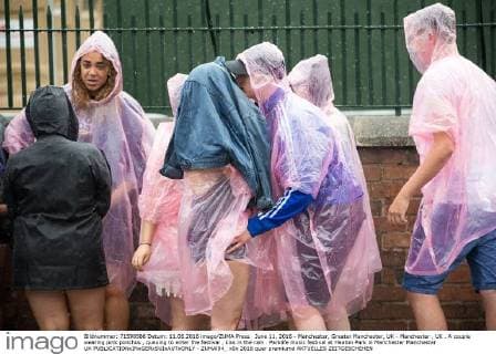 June 11, 2016 - Manchester, Greater Manchester, UK - Manchester , UK . A couple wearing pink ponchos , queuing to enter the festival , kiss in the rain . Parklife music festival at Heaton Park in Manchester Manchester UK  - ZUMAl94_