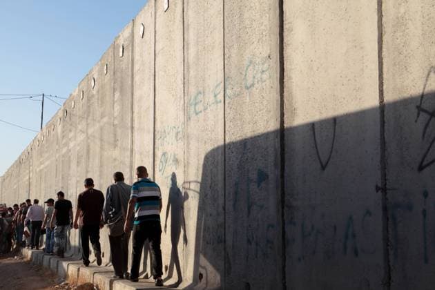 June 24, 2016 - Jerusalem, Israel - Palestinian men are walking next to the separation wall towards the Israeli military on Qalandia between the cities of Ramallah and Jerusalem, to enter to Jerusalem city for worship in Al-Asqa Mosque during Ramadan in third Friday. West Bank of Palestine. On 24 June 2016. Jerusalem Israel  - ZUMAn230