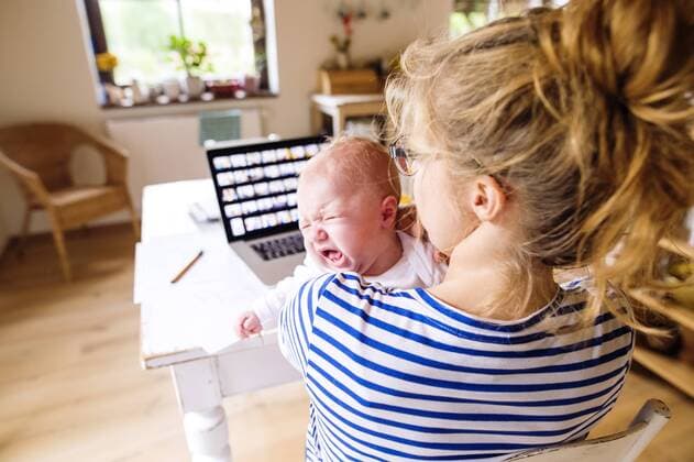 Mother at desk at home holding crying baby model released Symbolfoto property released  HAPF000475