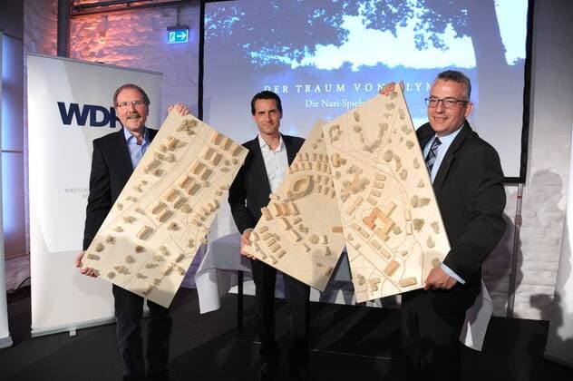 Produzent Kay Siering (m) überreicht das Modell des Olympischen Dorfes an Sammlungsleiter Wolfgang Lewitzki (l) und Geschäftsführer Sebastian Conrad (r) am 12.07.2016 bei dem Preview Der Traum von Olympia – Die Nazi-Spiele von 1936 . Bei diesem feierlichen Anlass wird dem Deutschen Sport & Olympia Museum das für die Dreharbeiten angefertigte Modell des Olympischen Dorfes übergeben