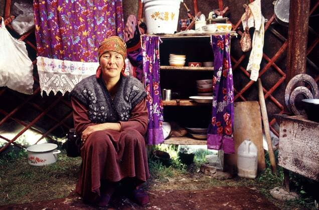 July 21, 2010 - Tian Mountains, Kazakstan - Kyrgyz or Kirgiz, Kirghiz. A woman sits in her yurt in front of her kitchen in a valley in the Tian Mountains, South Kazakhstan. Many Kazakhs maintain a semi nomadic existence, moving with herds, flocks and yurts from theit collective farms to summer pastures every year. The Tian Mountains lie on the southeastern border of Kazakstan and not only provide the nomadic people of Kazakstan an area which to roam freely, but also some spectacular views and scienery. Here in the remote mountain regions many traditional activities cintinue unchanged for many years. - ZUMAr126