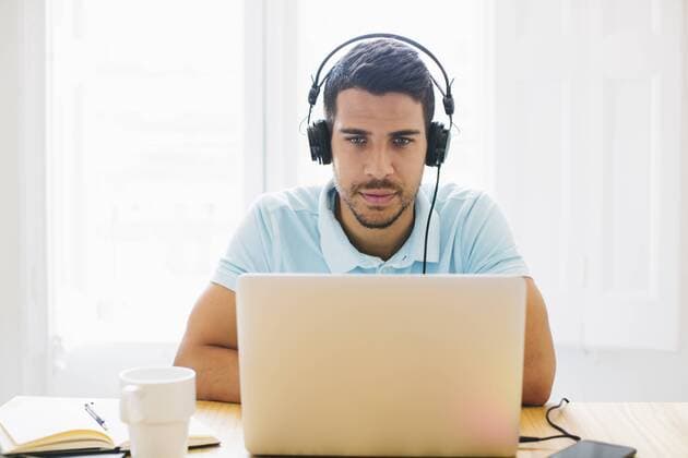 Young man in office wearing headphones and using laptop model released Symbolfoto property released  EBSF001530