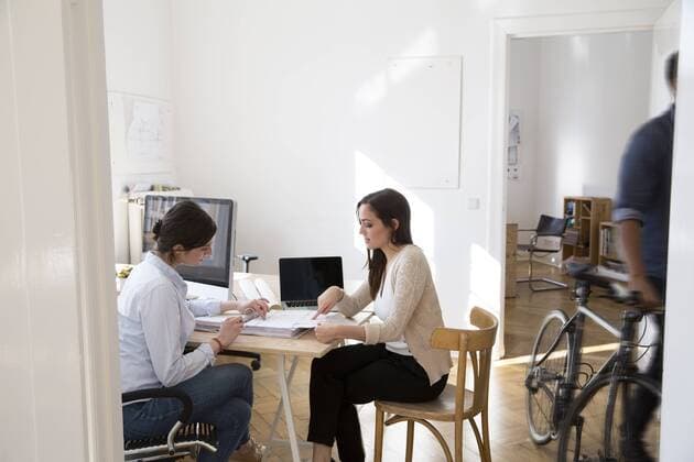 Two women discussing documents in office model released Symbolfoto property released  FKF001885