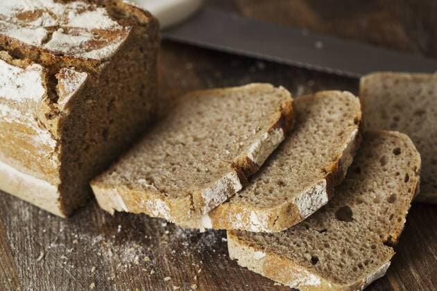 Close up of a loaf and slices of freshly baked bread on a wooden chopping board. Close up of a loaf and slices of freshly baked bread on a wooden chopping board.  21803