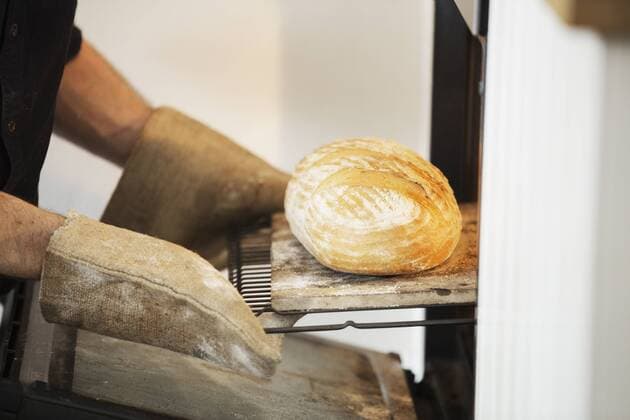 Close up of a baker taking a freshly baked loaf bread out of an oven. Close up of a baker taking a freshly baked loaf bread out of an oven.  21824