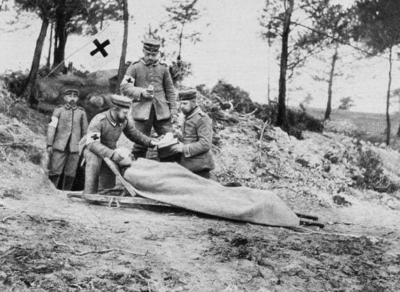 World War I 1914-1918: Wounded German soldier on a stretcher being treated behind the trenches by a field medical team displaying the symbol of the Red Cross, 1915. Medicine First Aid Warfare Casualty WHA  !ACHTUNG AUFNAHMEDATUM GESCHÄTZT! Copyright: WHA UnitedArchives0510004623