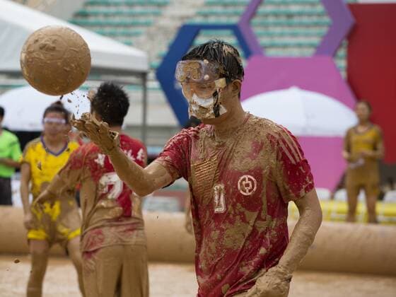 Schlammfußball in Peking BEIJING, CHINA - AUGUST 13: A player handles the ball during the first station match of 2016 Swamp Soccer China tournament at Yuetan Park on August 13, 2016 in Beijing, China. Different from former years matches in China, there were four teams composed entirely of women this year. The Swamp Soccer World Cup features a team of extreme football players that play in bogs or swamps. This sport is said to have originated in Finland, with the aim of helping athletes and soldiers exercise, due to the physical demands of the sport.  CFP490208068