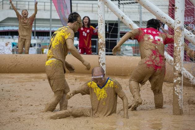 Schlammfußball in Peking BEIJING, CHINA - AUGUST 13: Players battle for the ball during the first station match of 2016 Swamp Soccer China tournament at Yuetan Park on August 13, 2016 in Beijing, China. Different from former years matches in China, there were four teams composed entirely of women this year. The Swamp Soccer World Cup features a team of extreme football players that play in bogs or swamps. This sport is said to have originated in Finland, with the aim of helping athletes and soldiers exercise, due to the physical demands of the sport.  CFP490208070