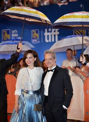 Director Rebecca Zlotowski (L) and actor David Bennent arrive under umbrellas at the Toronto International Film Festival premiere of Planetarium at Roy Thomson Hall on a rainy night in Toronto, Canada on September 10, 2016.  TOR2016091034 CHRISTINExCHEW
