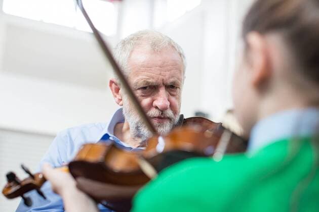 September 27, 2016 - Liverpool, Merseyside, UK - Liverpool , UK . Labour Party leader JEREMY CORBYN is shown how to play the violin by JESSICA KELLY (10) during a visit to Faith Primary School in Liverpool , where he listens to and then joins in with the school orchestra Liverpool UK  - ZUMAl94_