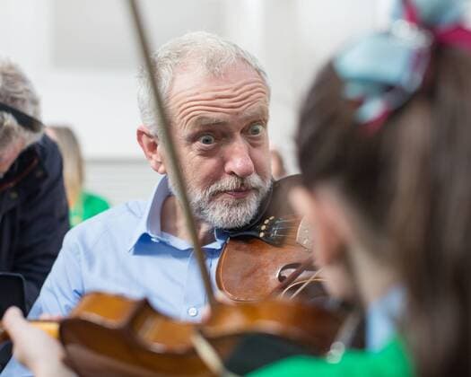 September 27, 2016 - Liverpool, Merseyside, UK - Liverpool , UK . Labour Party leader JEREMY CORBYN is shown how to play the violin by JESSICA KELLY (10) during a visit to Faith Primary School in Liverpool , where he listens to and then joins in with the school orchestra Liverpool UK  - ZUMAl94_